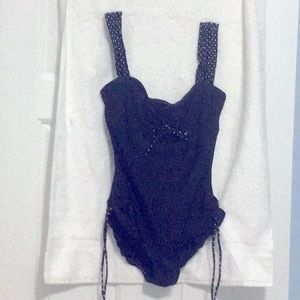 This cute little one piece swimsuit, has polka dot trim on the straps and ties.